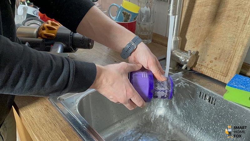 Ein Dyson HEPA-Filter vom Akkusauger wird unter fließend Wasser gereinigt
